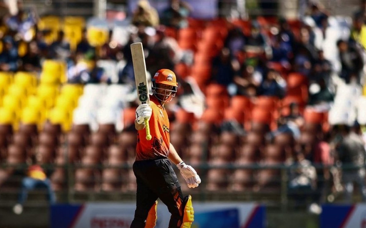 Dawid Malan in Chitwan Rhinos orange raising his bat after reaching his half-century at the TU Cricket Ground in Kirtipur