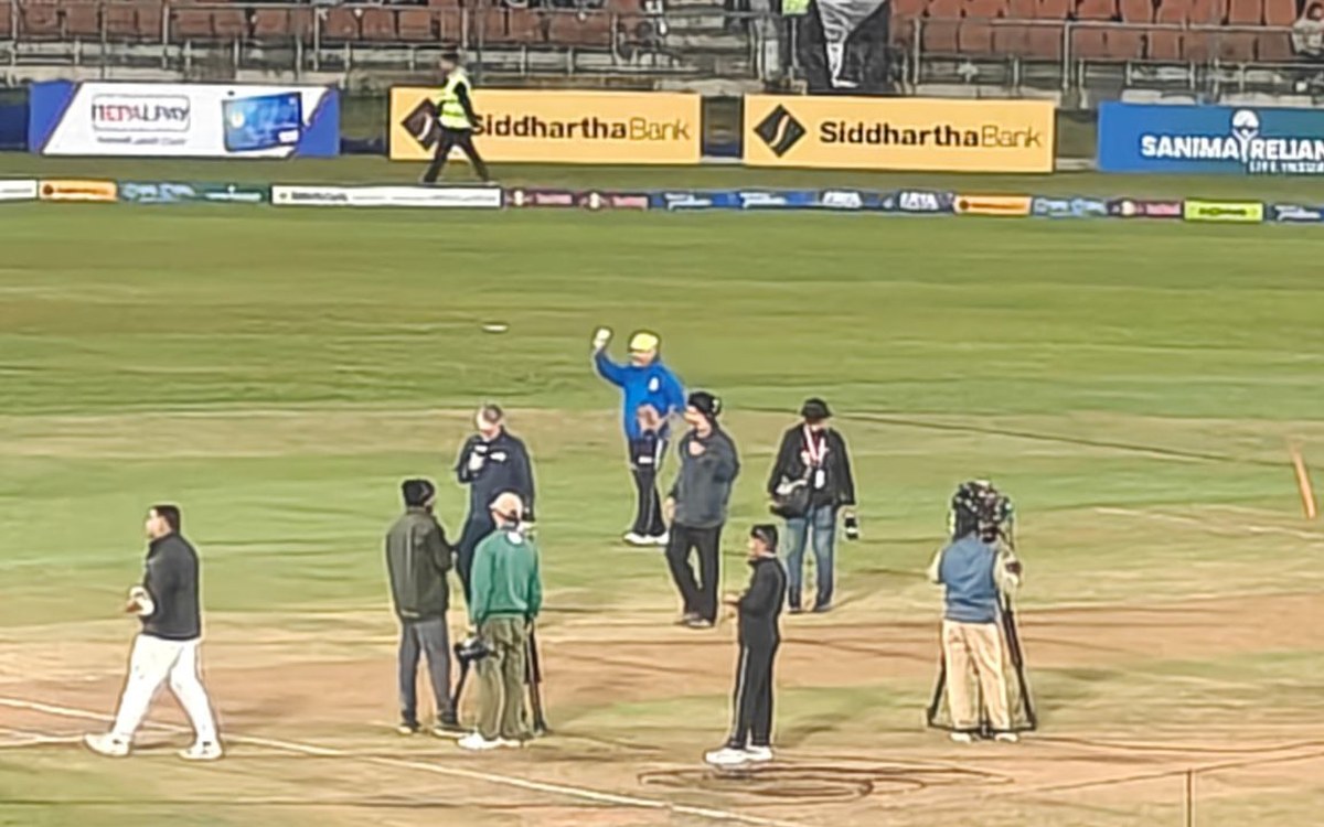 Officials and players on the pitch at TU Ground in Kirtipur on Saturday night during the delayed Match 8